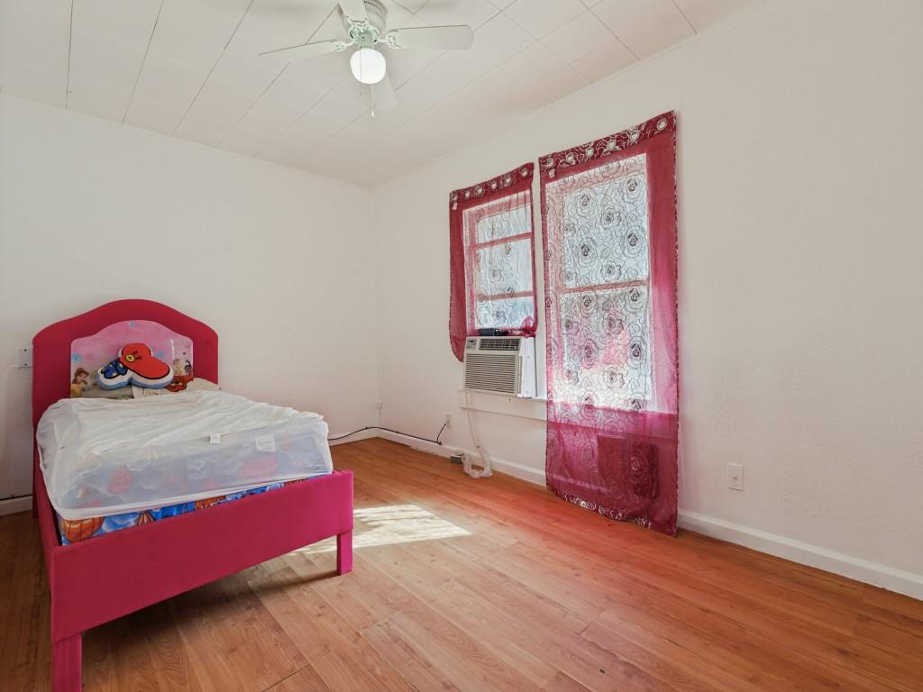 Room featuring wood-finish flooring, a paneled ceiling with a central light fixture and fan, and dual windows
