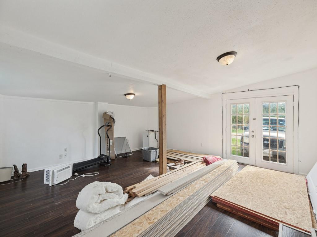 Interior space featuring dark wood-finish flooring, exposed structural post, and double glass-paneled doors