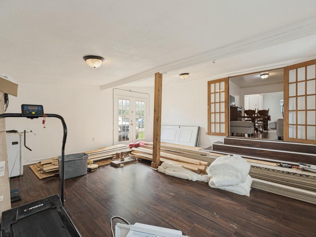 Wood-finish flooring, exposed structural post, double-pane glass entry doors, and wood-framed French doors featuring multi-pane glass