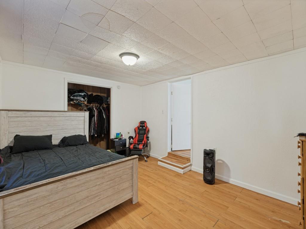 Room featuring wood-finish flooring, a recessed closet, a ceiling-mounted light fixture, and a stepped threshold entry
