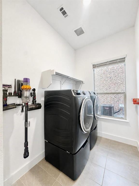 Laundry area featuring large-format tile flooring, a window with natural light, and wall-mounted shelving Laundry area featuring large-format tile flooring, a window with natural light, and wall-mounted shelving