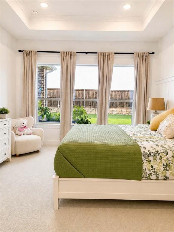 Tray ceiling, recessed lighting, and large windows with exterior access to a fenced yard