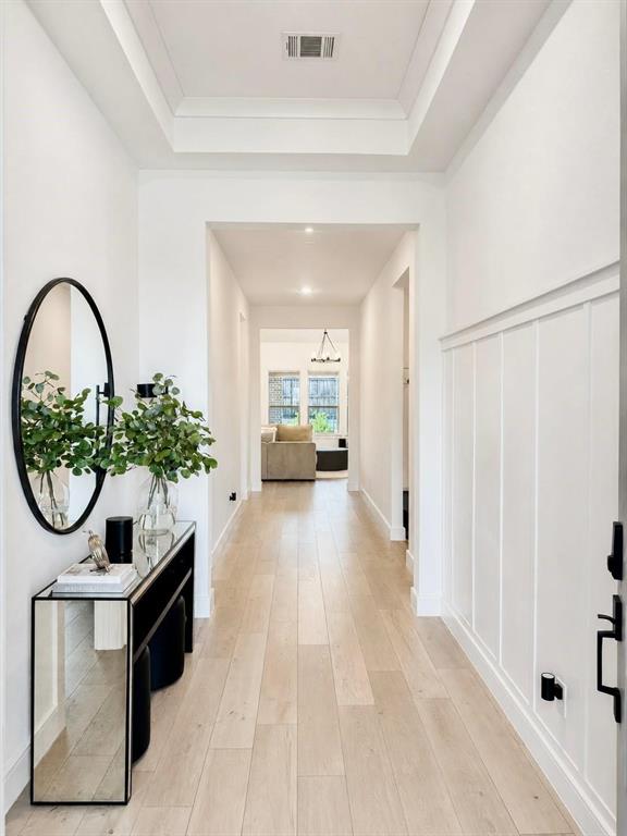 Entryway featuring wood-finish flooring, a tiered tray ceiling, and wainscoting detail Entryway featuring wood-finish flooring, a tiered tray ceiling, and wainscoting detail