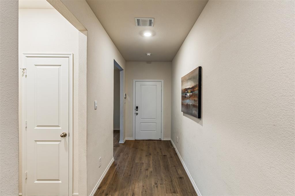 Neutral-toned interior featuring wood-finish flooring, a multi-panel entry door with electronic deadbolt, and recessed ceiling lighting