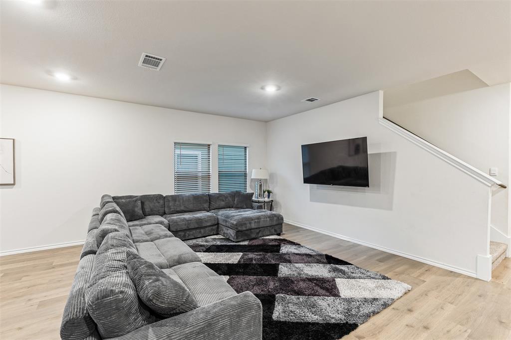 Neutral interior space featuring wood-finish flooring, recessed lighting, and a staircase with a wooden handrail
