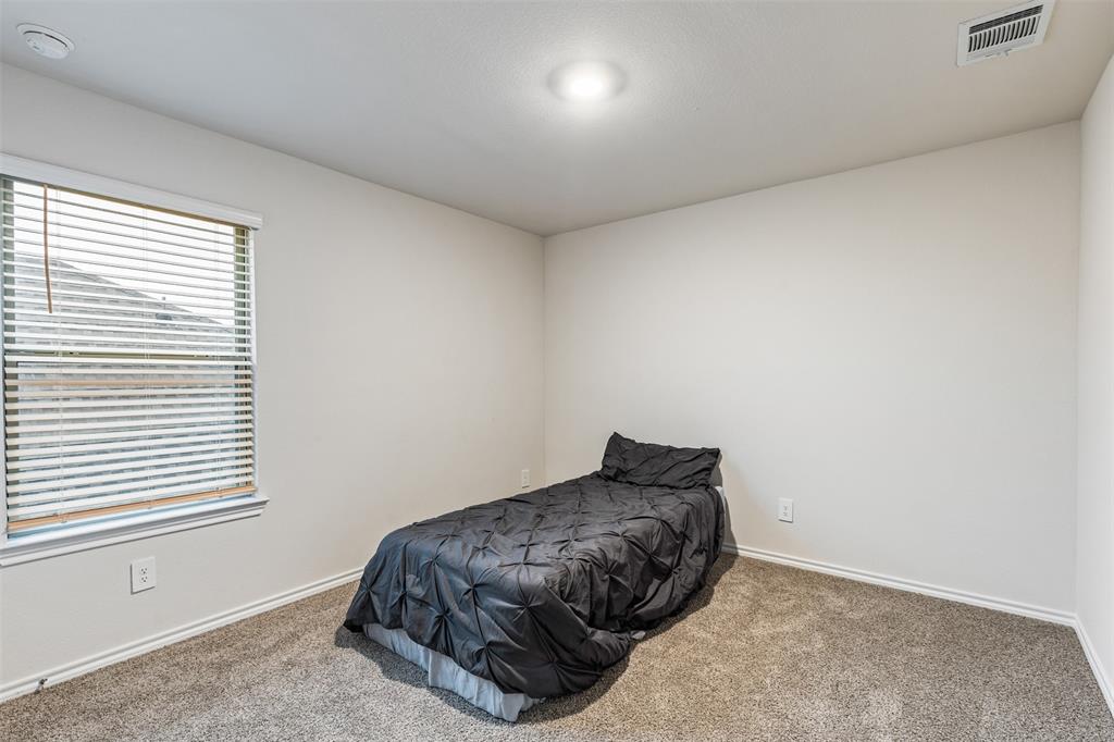 Neutral-toned interior room featuring wall-to-wall carpeting, a multi-pane window with horizontal blinds, and a flush-mount ceiling fixture