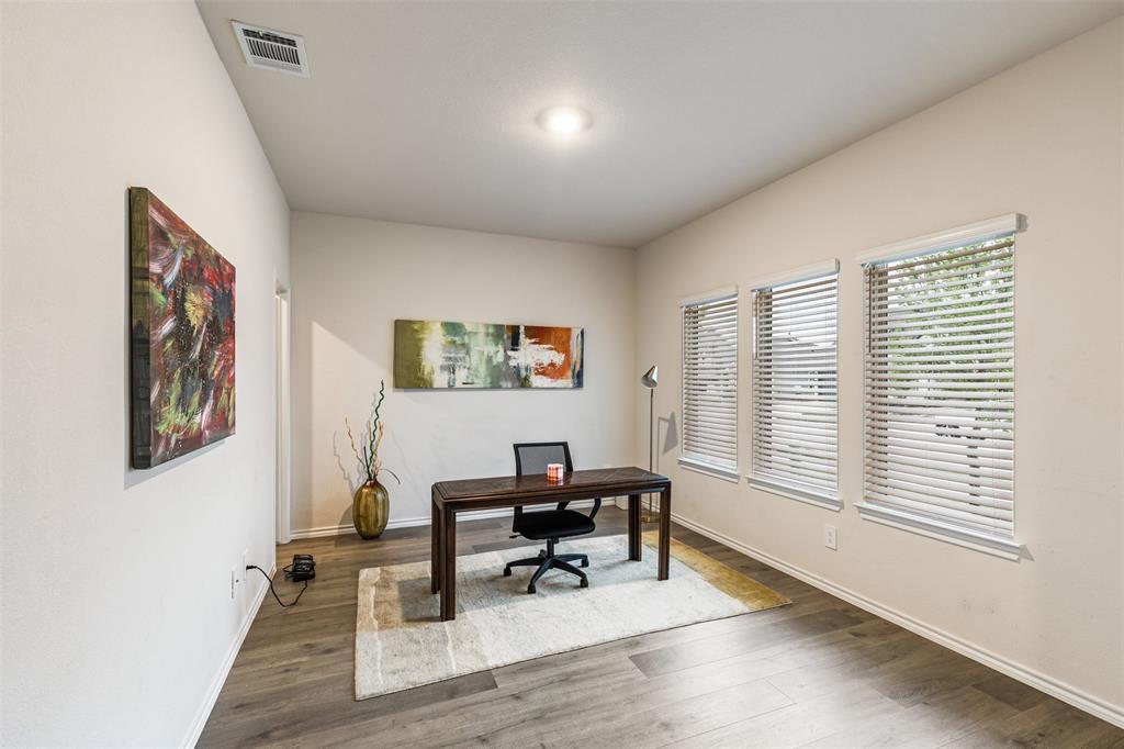 Wood-finish flooring, neutral wall tones, and triple windows with horizontal blinds