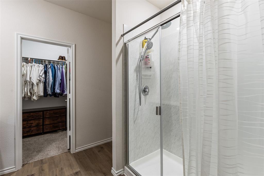 Walk-in shower with a sliding glass door, surround tile, and a handheld showerhead
