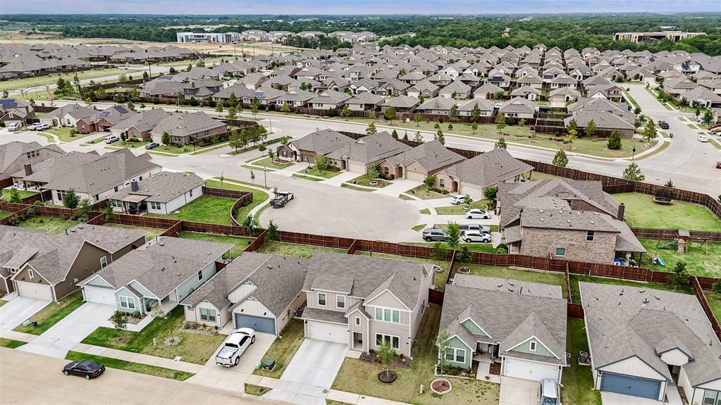 Aerial perspective of a suburban neighborhood featuring residential homes, paved streets, concrete driveways, and private fenced backyards