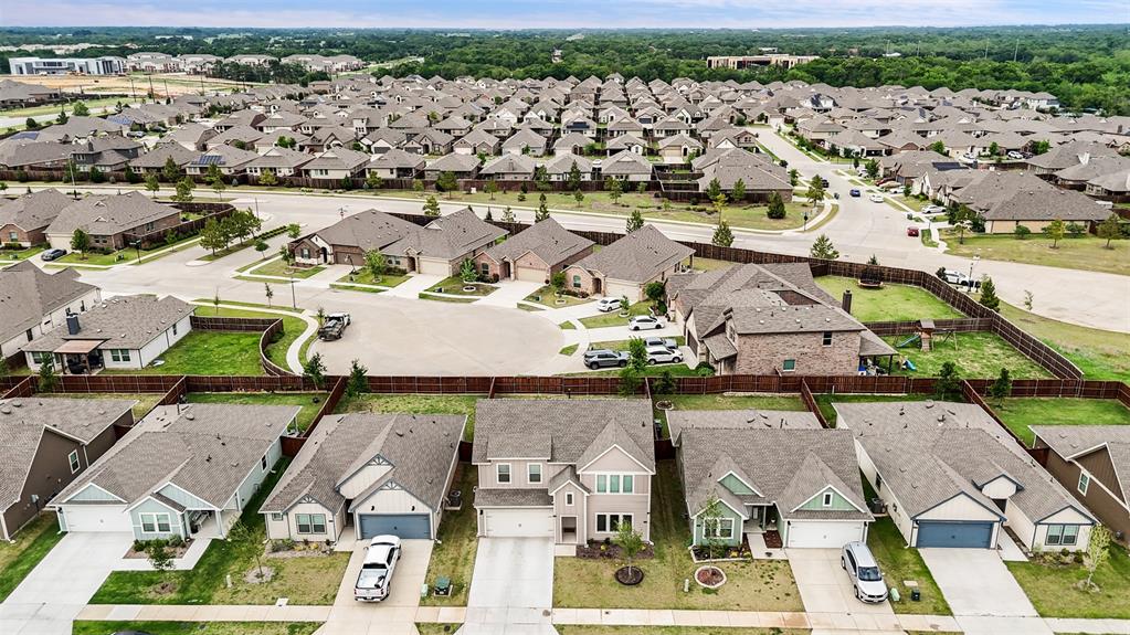 Aerial perspective of a suburban neighborhood featuring residential homes, multi-story dwellings, paved roadways, cul-de-sacs, and wood-fencing property boundaries