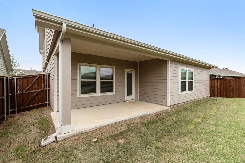 Rear exterior featuring a covered concrete patio, horizontal lap siding, and a wooden privacy fence