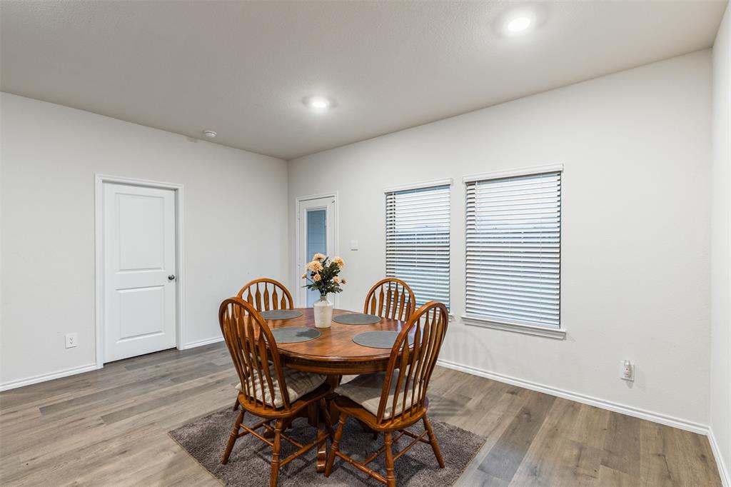Neutral-toned interior featuring wood-finish flooring, recessed lighting, dual windows with horizontal blinds, and a single-panel door