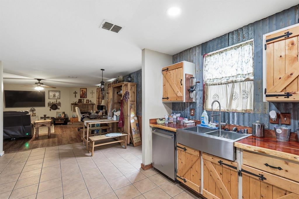 Kitchen featuring custom wood cabinetry with sliding barn-style doors, corrugated metal wall accents, a stainless steel apron-front sink, and polished wood-finish countertops