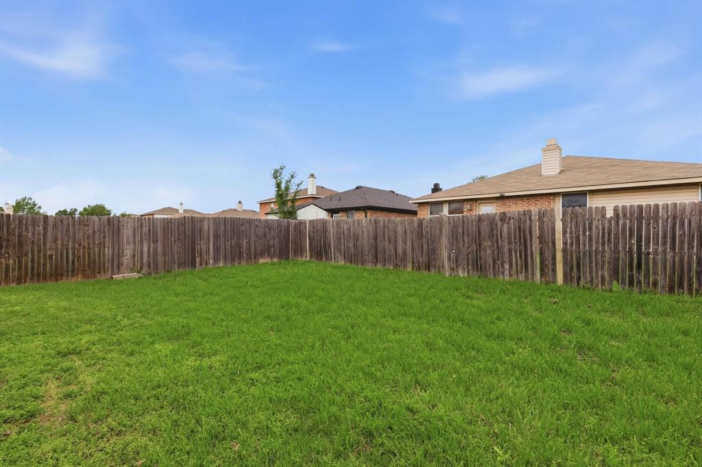 Backyard featuring a manicured lawn and perimeter wood fencing