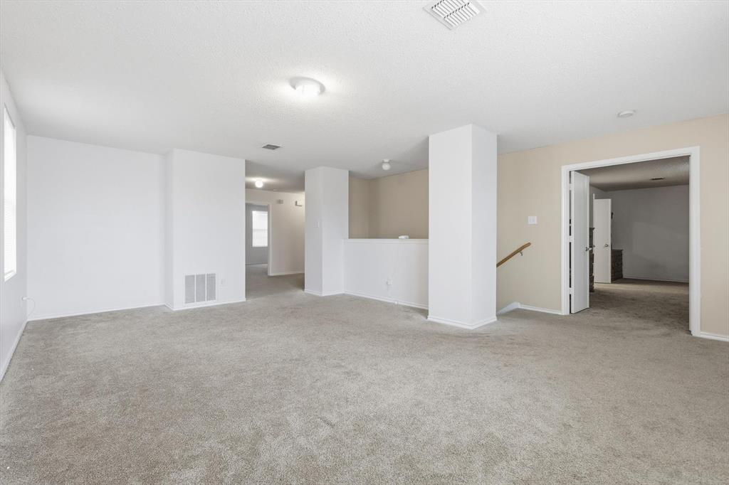 Expansive interior space featuring neutral wall tones, wall-to-wall carpeting, flush-mount lighting fixtures, and a structural column