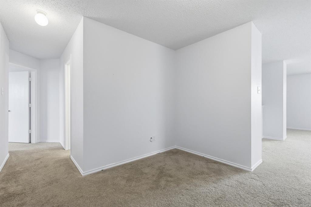 Neutral interior space featuring textured ceilings, light-toned carpeting, and minimalist walls