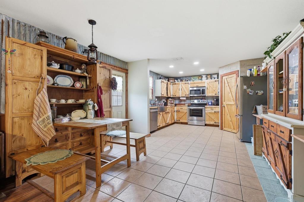 Kitchen featuring custom wood cabinetry with X-brace detailing, stainless steel appliances, recessed lighting, and tile flooring