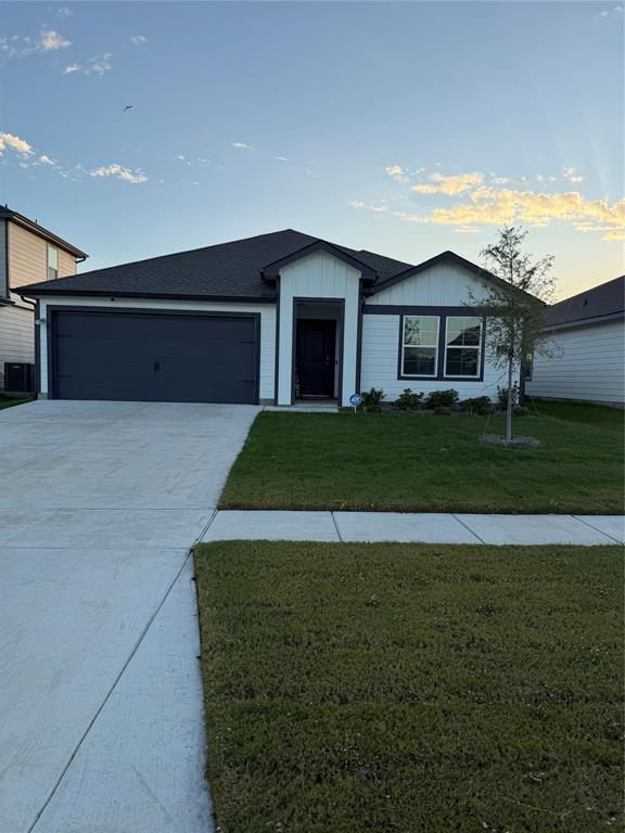 Single-story exterior featuring white vertical and horizontal siding with dark trim, a two-car garage, asphalt shingle roofing, and a concrete driveway