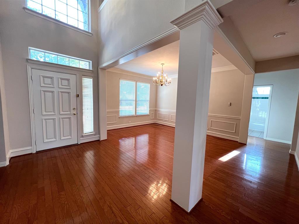 Entryway featuring double-height ceilings, wood-finish flooring, wainscoting, an arched transom window above the front door, and a decorative chandelier