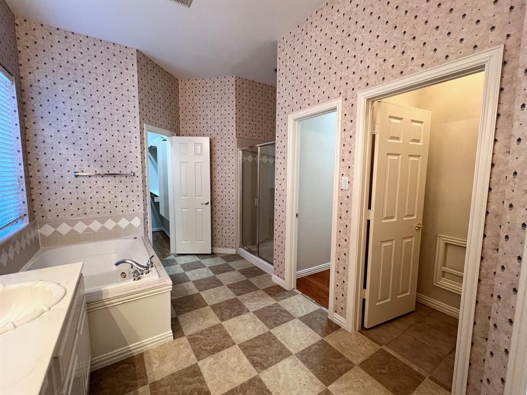 Soaking tub with tile surround, glass-enclosed shower, dual interior doors, and checkerboard-patterned flooring