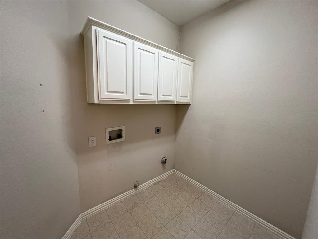 Wall-mounted white cabinetry with recessed-panel doors and neutral tile flooring