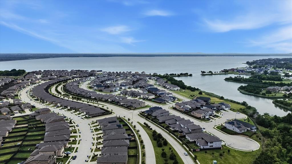 Aerial perspective of a planned community situated along a prominent lakefront with curving residential streets, diverse single-family rooflines, and expansive shoreline access