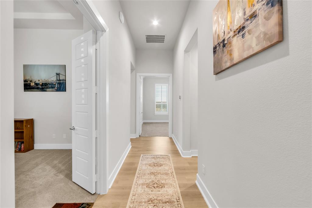 Hallway featuring neutral wall tones, light wood-finish flooring, recessed lighting, and a multi-panel interior door