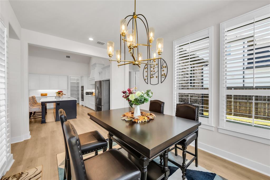 Dining area featuring a multi-light metal chandelier, wood-finish flooring, and white plantation shutters