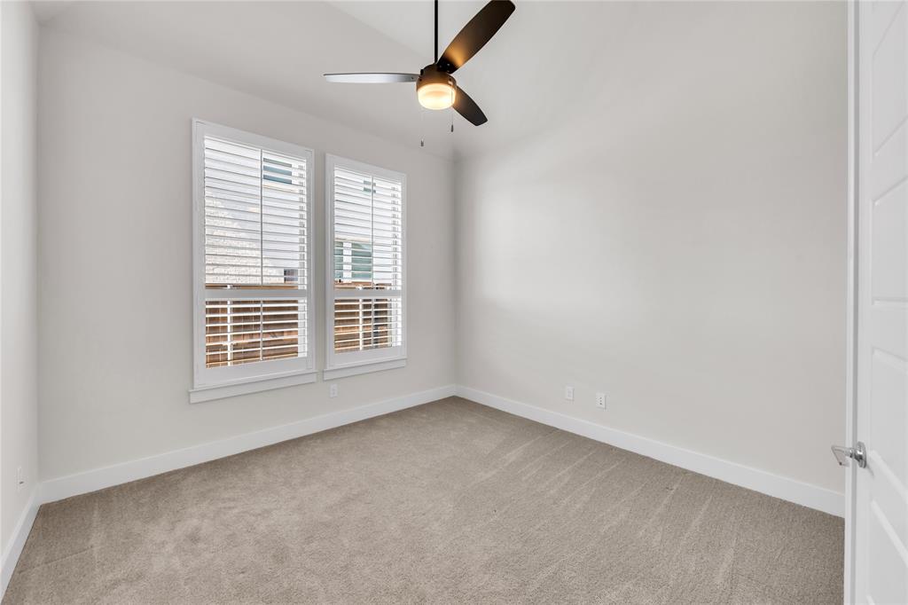 Neutral interior featuring wall-to-wall carpeting, dual windows with plantation shutters, and a central ceiling fan