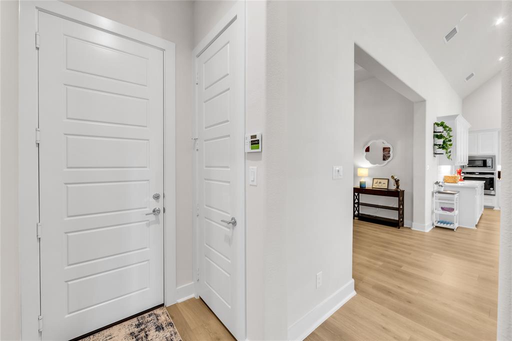 Entryway featuring five-panel doors with satin nickel hardware, wood-finish flooring, and vaulted ceilings