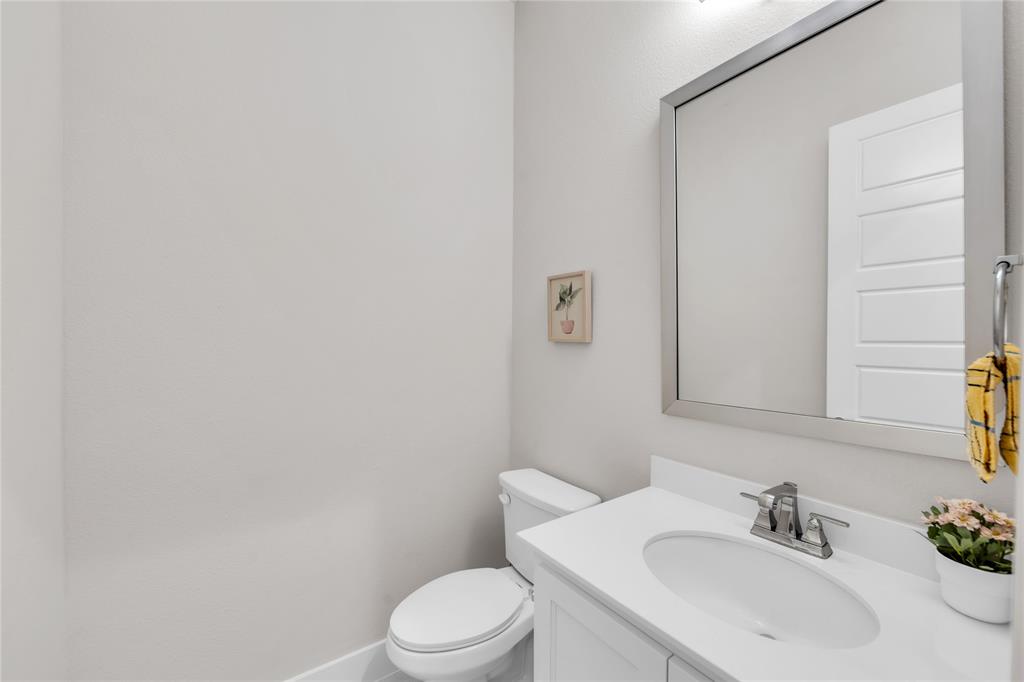Vanity with a white countertop, undermount sink, chrome faucet, wall-mounted mirror, and a two-piece toilet