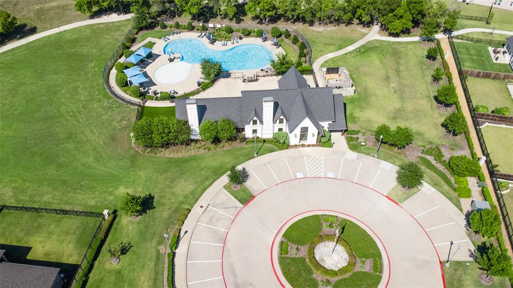 Community facility featuring an outdoor swimming pool, paved circular parking area, expansive manicured grounds, and mature landscaping