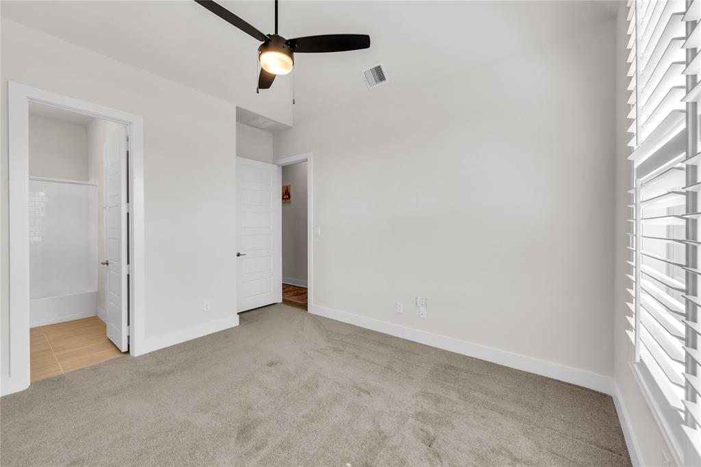 Room featuring neutral wall-to-wall carpeting, high ceilings with a central matte black ceiling fan, and plantation shutter window treatments