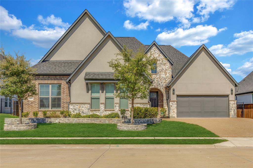 Multi-gabled exterior featuring stucco and stone facade, stone-trimmed garden beds, multi-car garage, and asphalt shingle roof Multi-gabled exterior featuring stucco and stone facade, stone-trimmed garden beds, multi-car garage, and asphalt shingle roof
