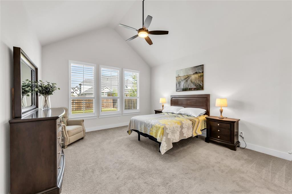 Vaulted ceilings, carpeting, three panel windows with shutters, and a ceiling fan with integrated lighting