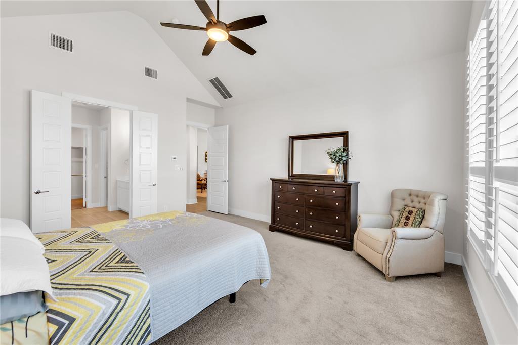 Vaulted ceilings featuring a central ceiling fan, plush carpeting, and adjustable louvered window shutters