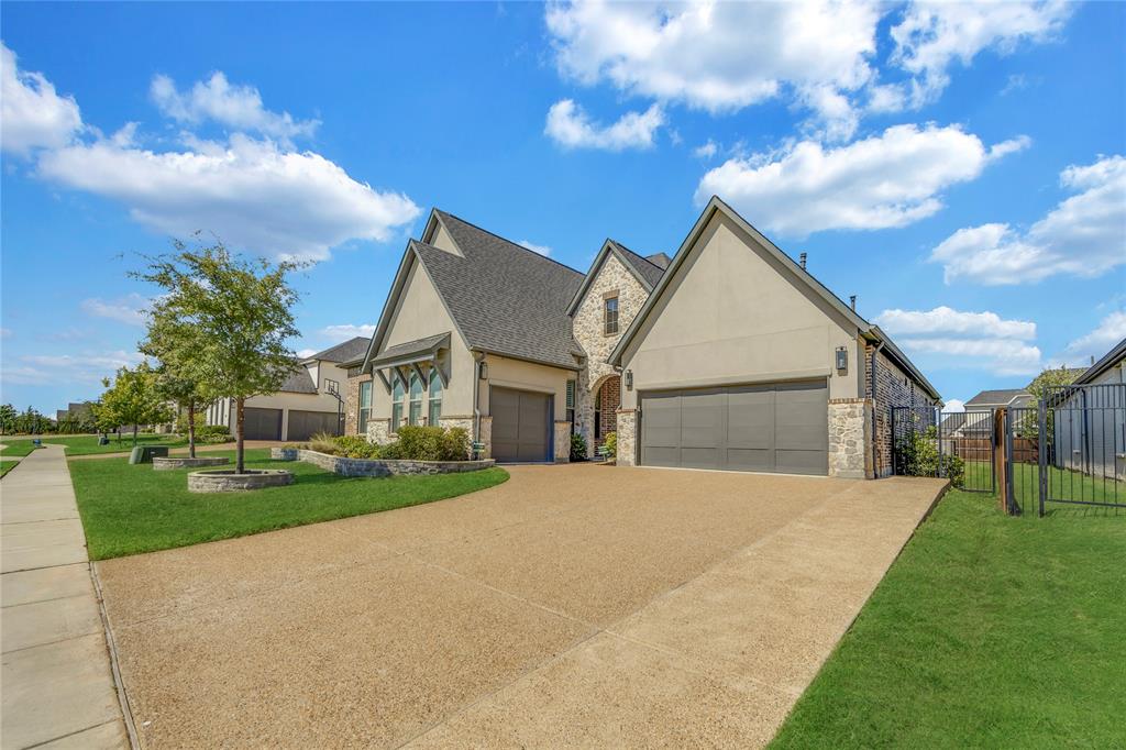 Stucco and stone exterior featuring a multi-gabled roofline, an expansive aggregate driveway, and an attached multi-car garage