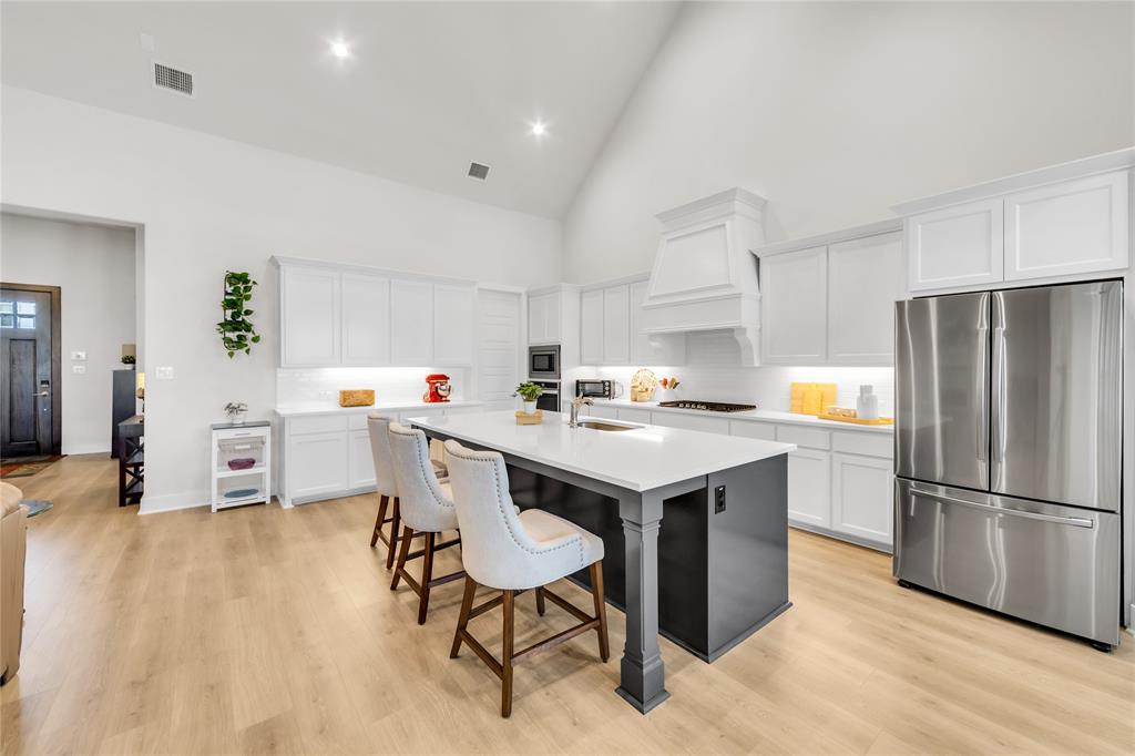 Kitchen featuring a vaulted ceiling, central island with a contrasting base, white cabinetry, light-toned wood-finish flooring, and recessed lighting