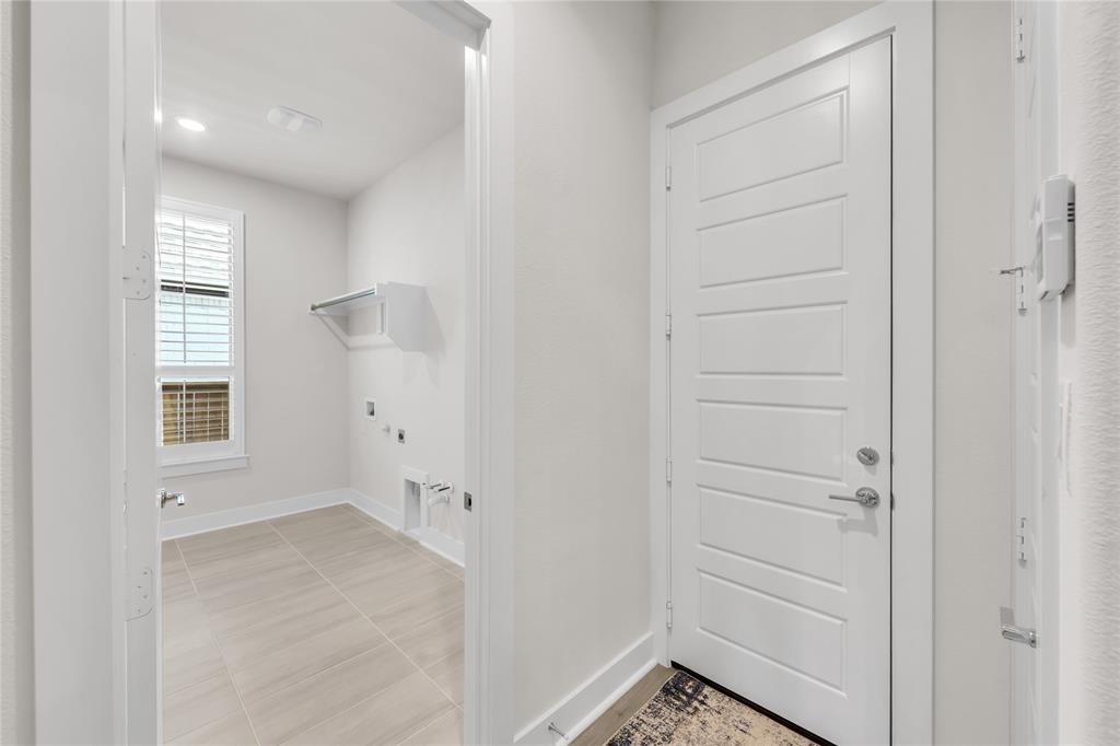 Utility area featuring ceramic tile flooring, a wall-mounted shelving unit, and a window with shutter-style blinds