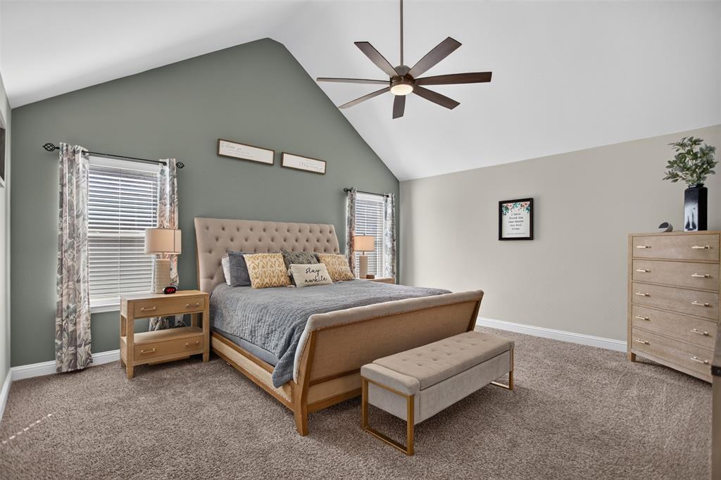 Vaulted ceiling featuring a central multi-blade ceiling fan, dual windows, and wall-to-wall carpeting