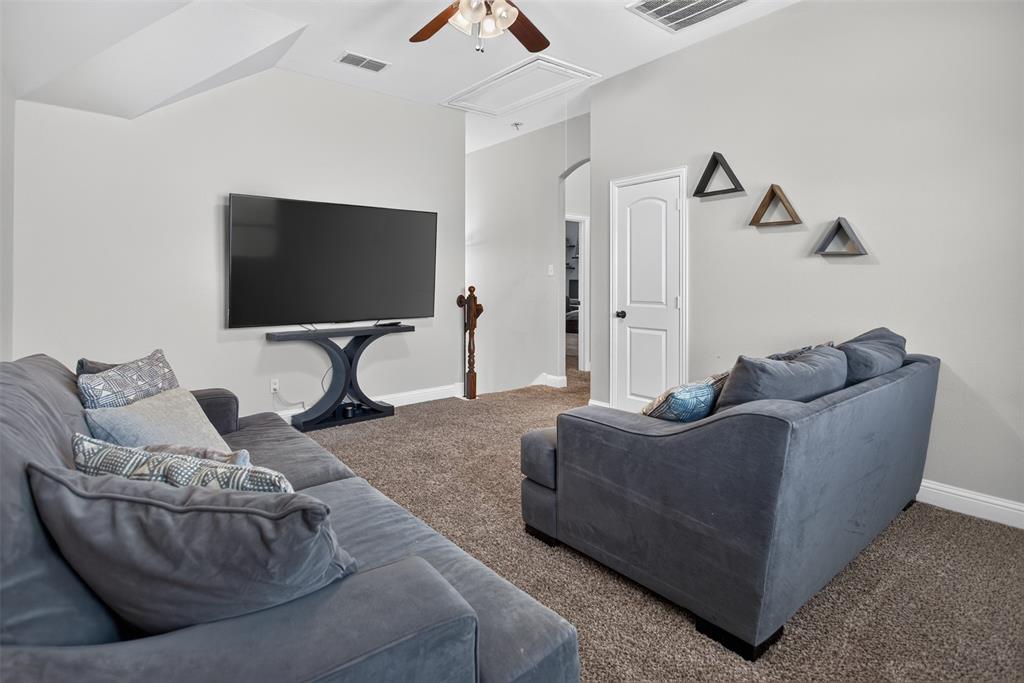 Neutral-toned room featuring high vaulted ceilings, wall-to-wall carpeting, an attached ceiling fan with lighting, and an arched entryway