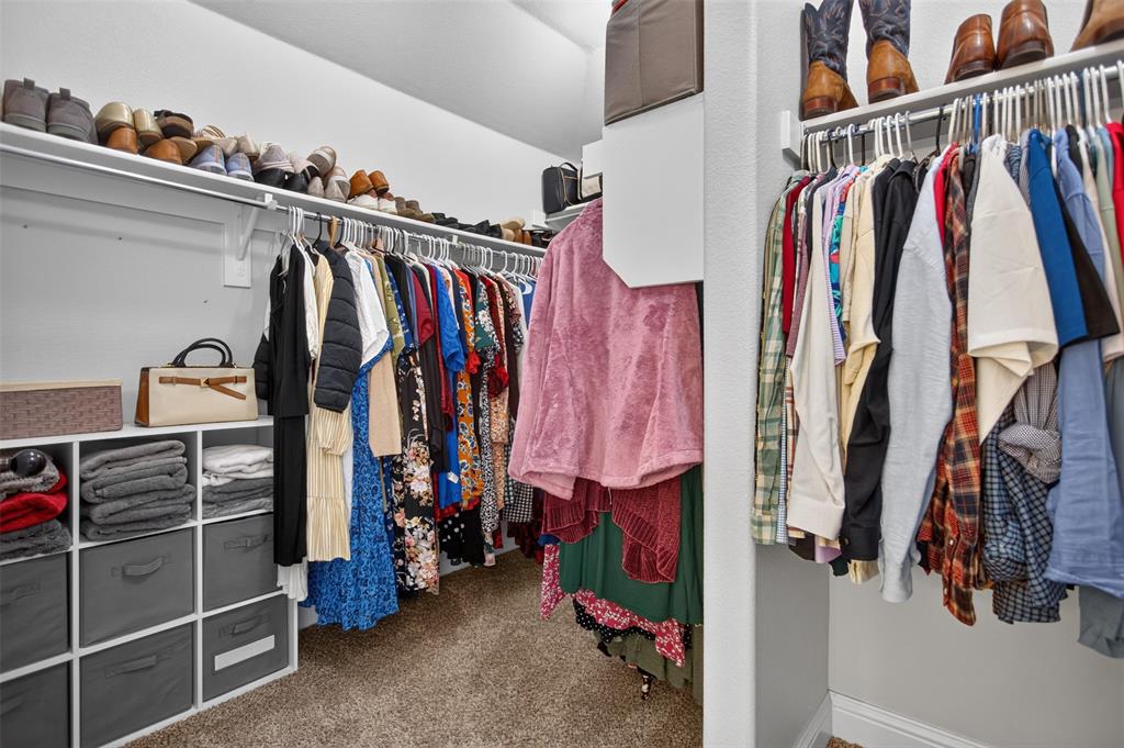 Walk-in closet featuring tiered clothing rods, integrated upper shelving, and custom built-in cubbies with storage bins
