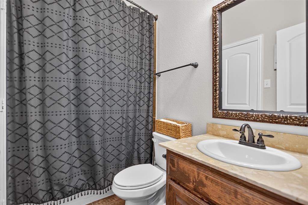 Bathroom vanity featuring a natural stone countertop, an integrated drop-in sink, a metal dual-handle faucet, and an ornate framed wall mirror