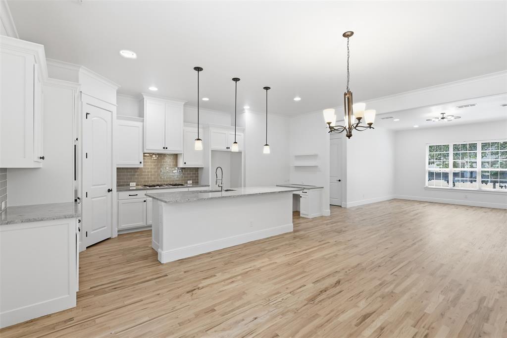 Kitchen featuring shaker-style cabinetry, stone countertops, a tile backsplash, wood-finish flooring, and pendant lighting