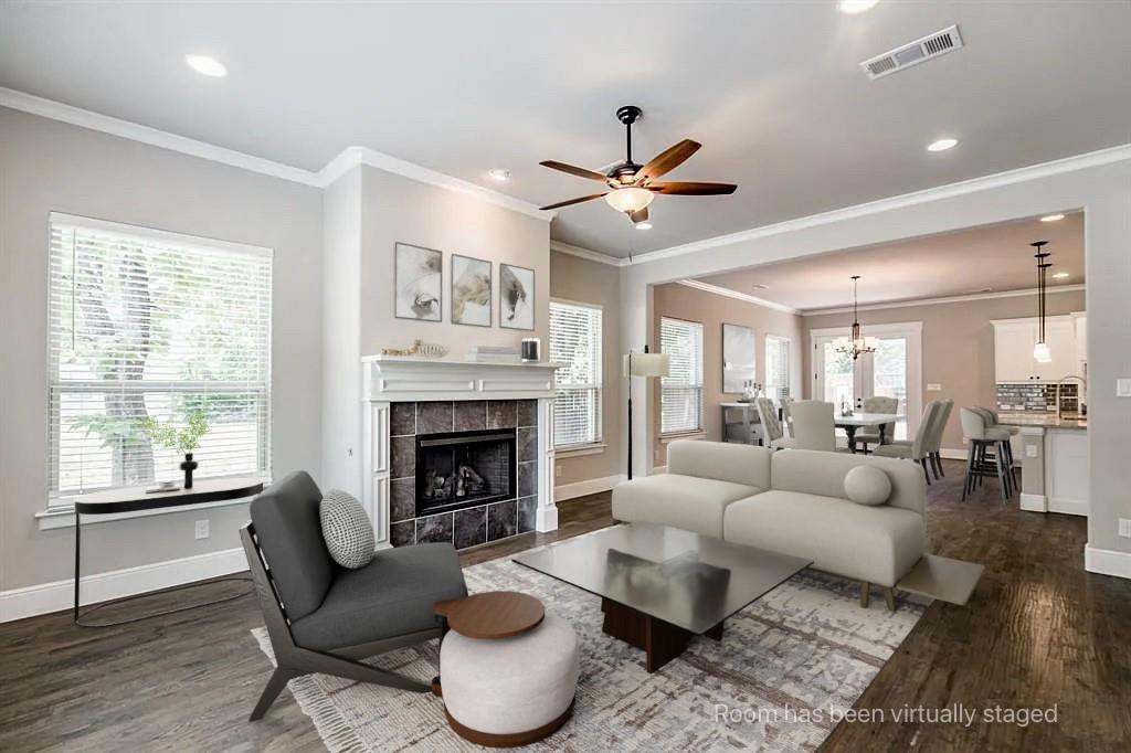 Living area featuring wood-finish flooring, recessed lighting, crown molding, a ceiling fan, and a tile-surround fireplace with a mantel