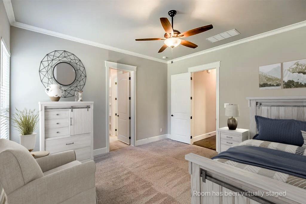 Neutral-toned bedroom featuring carpeting, multi-blade ceiling fan with integrated lighting, and crown molding