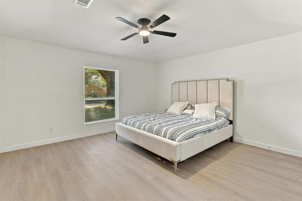 Neutral-toned wood-finish flooring, ceiling fan with integrated lighting, and a single-pane window