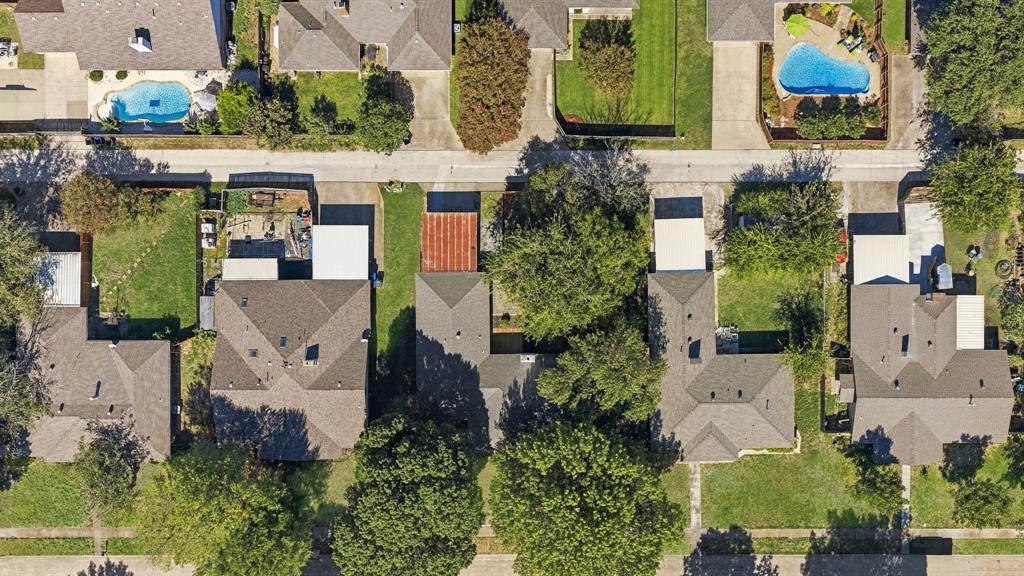 Aerial perspective featuring residential lots with mature canopy trees, paved driveways, and expansive green spaces