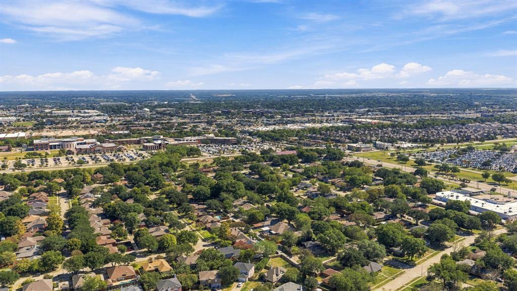 Aerial perspective of the residential area featuring mature tree canopy, dense landscaping, established road infrastructure, and expansive horizon