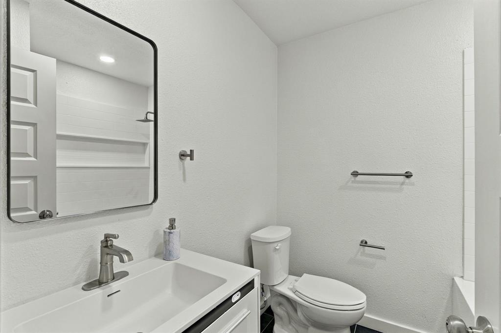 Bathroom featuring a vanity with an integrated sink, brushed metal faucet, rectangular mirror with a black frame, and wall-mounted hardware